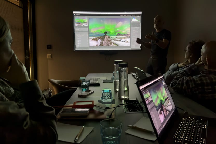 Photographers learning post-processing techniques on laptops during a photography workshop